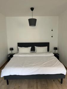 a bedroom with a large white bed with a black headboard at TMJ Apartment 1 in Düsseldorf