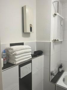 Baño con una pila de toallas en un estante en Düs Apartment 1, en Düsseldorf