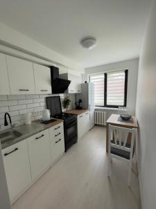 a kitchen with white cabinets and a table in it at Radvilų apartamentai in Radviliškis