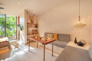 a living room with a table and a couch at Amazing 1BR Tulum Jungle with Restaurant, Pool and Gym in Tulum
