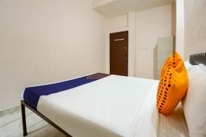 a bedroom with a bed with an orange pillow on it at SPOT ON 66974 Hotel shri gurukripa in Gwalior