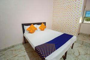 ein Bett mit orangefarbenen und blauen Kissen darauf in der Unterkunft SPOT ON 66974 Hotel shri gurukripa in Gwalior