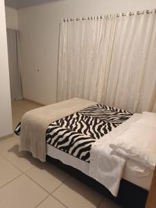 a zebra print bed in a room with a window at Pousada Tertulia Apartamento completo em Lages! in Lages