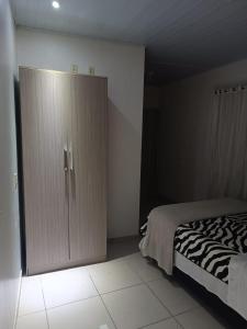 a bedroom with a bed and a large wardrobe at Pousada Tertulia Apartamento completo em Lages! in Lages