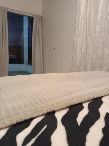 Una cama con una manta de cebra encima. en Pousada Tertulia Apartamento completo em Lages!, en Lages