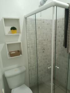 a bathroom with a toilet and a glass shower at Pousada Tertulia Apartamento completo em Lages! in Lages