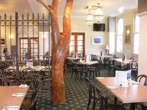 ein Restaurant mit Tischen und Stühlen und einem Baum in der Mitte in der Unterkunft The Yarrawonga Hotel in Yarrawonga