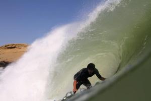 un hombre montando una ola en una tabla de surf en el océano en Hospedaje Talareño Hokua Suite, en Talara