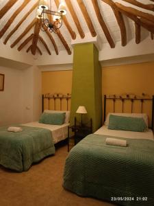 una camera con due letti con lenzuola verdi di La Laguna ad Almedinilla