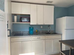 a kitchen with white cabinets and a white refrigerator at Neverland in Jacksonville +8 photos