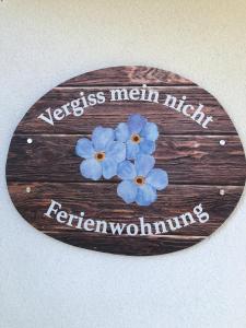 a wooden sign with blue flowers on it at Vergiss mein nicht in Grinzens