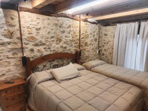 a bedroom with two beds in a room with stone walls at Matandrino in Prádena +24 photos