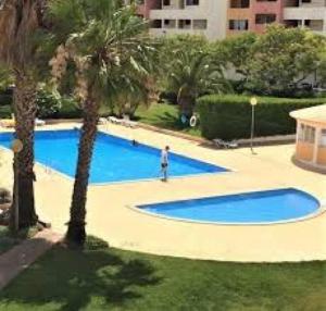 a person standing next to a large blue swimming pool at Onda Verde in Albufeira