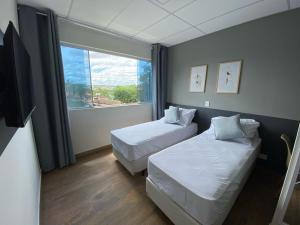a hotel room with two beds and a window at NOBRE HOTEL COTIA in Cotia