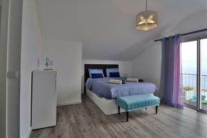 ein Schlafzimmer mit einem Bett und einem blauen Hocker darin in der Unterkunft Vila Castro in Estreito da Calheta + 42 Fotos