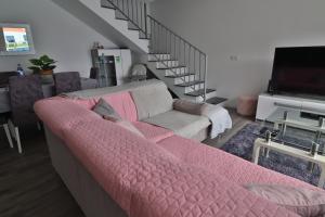 a living room with a pink couch and a staircase at Vila Castro in Estreito da Calheta