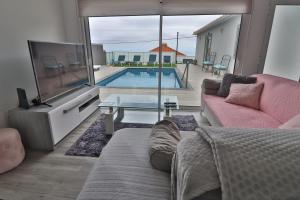 a living room with a couch and a tv and a pool at Vila Castro in Estreito da Calheta
