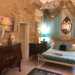 1 dormitorio con cama y pared de piedra en Knights In Malta, en Naxxar