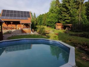 a swimming pool in front of a house with solar panels at Magasbükk Pataka kulcsosház in Izvoare