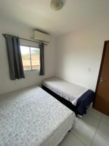 - 2 lits dans une petite chambre avec fenêtre dans l'établissement Apartamento em Ilha De Itamaracá, à Vila Velha