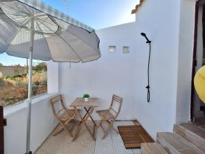 un patio con mesa, 2 sillas y sombrilla en Typical house in Algarve 5m from beach, en Porches