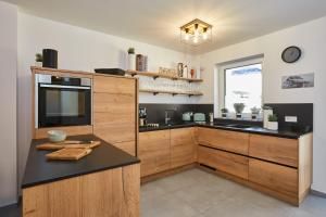 a kitchen with wooden cabinets and a black counter top at 3KORNHAUS - Das neue Alpendomizil in Garmisch-Partenkirchen
