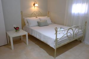 a bed with white pillows and a table in a room at Vintage Garden House in Doxato