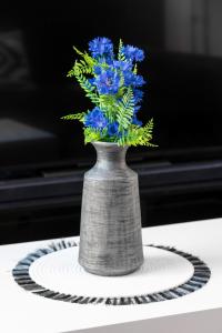 a vase filled with blue flowers on a plate at Skackavá apartmán v centre Banskej Bystrice, 24h self check-in in Banská Bystrica