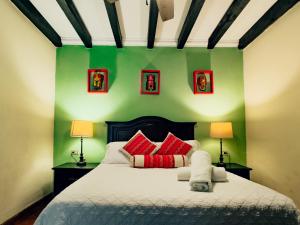 a bedroom with a bed with red pillows and green walls at Casa Mia Hotel in Antigua Guatemala