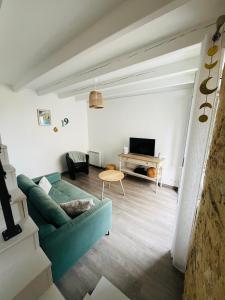 een woonkamer met een groene bank en een tafel bij Le 19 Rue **,Maison de charme proche du Puy du Fou in Mouchamps