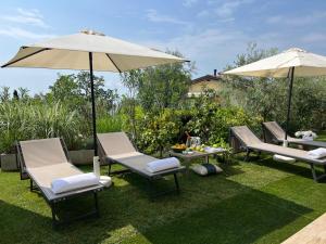 un groupe de chaises et de parasols sur l'herbe dans l'établissement Villa Diamante del Garda & Spa, à Toscolano Maderno