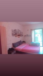 a bedroom with a bed with a pink mattress and a window at Casa di Penna in Barberino di Mugello