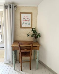 een tafel met een stoel en een plant erop bij Le 19 Rue **,Maison de charme proche du Puy du Fou in Mouchamps