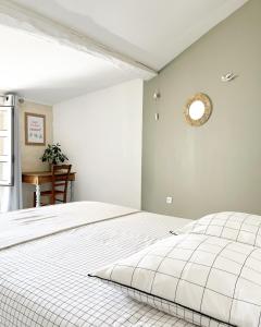 a bedroom with a white bed with a clock on the wall at Le 19 Rue **,Maison de charme proche du Puy du Fou in Mouchamps