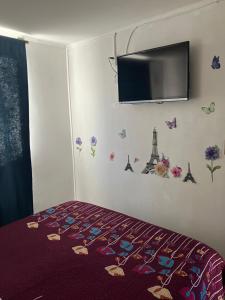 1 dormitorio con 1 cama y TV en la pared en Piso 5 Con estacionamiento - Sin Ascensor, en Copiapó