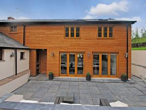 a wooden building with glass doors and a courtyard at Exmoor Farmhouse in Tiverton +3 photos