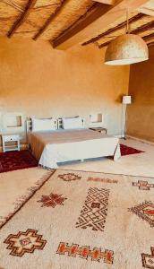 - une chambre avec un lit dans une pièce dotée d'un tapis dans l'établissement RIAD AMAN SKOURA, à Skoura