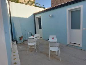 a patio with white tables and chairs next to a blue building at B&B Il Borgo delle Emozioni in Dolianova