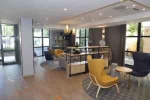 a living room with yellow chairs and tables and windows at Floridianes by HRI in Aix-en-Provence