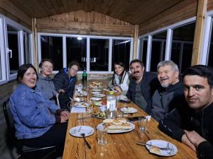 a group of people sitting around a wooden table at Xinaliq İzzet's Riverside Home Stay in Xınalıq