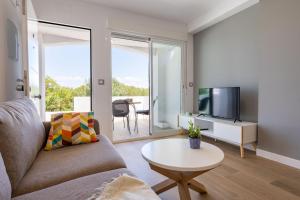 sala de estar con sofá, TV y mesa en paqo lodge Laguna del Portil, a 400 metros de la playa en El Portil
