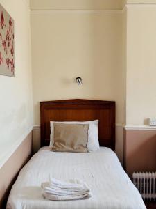 Bett mit weißer Bettwäsche und einem Kopfteil aus Holz in der Unterkunft Grosvenor Hotel Rugby in Rugby