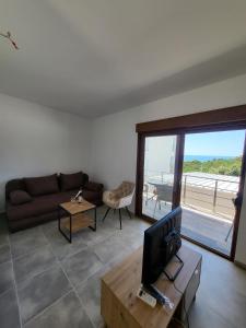a living room with a couch and a tv and a balcony at Bungalovi Arabela in Utjeha