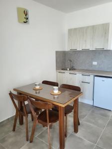 uma cozinha com uma mesa de madeira com cadeiras e um lavatório em Arabela Bungalovi em Utjeha