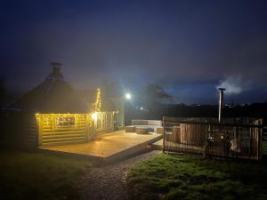 a house with lights on a deck at night at Off GRID Hobbit Hut with Wood Burning Hot tub NO SHOWER in Hapton