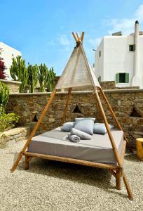 a hammock bed with a wooden frame in a yard at Sofos Suites Mykonos in Mýkonos City