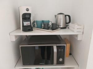 a white shelf with a microwave and cups on it at B&B Il Borgo delle Emozioni in Dolianova