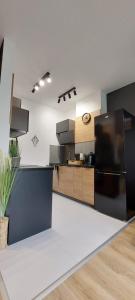 a kitchen with a black refrigerator and wooden cabinets at Apartamenty Trzy Kopce SKI & BIKE & SAUNA in Ustroń