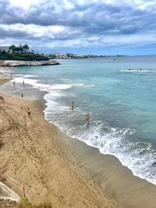 une plage avec des gens jouant dans l'eau dans l'établissement CASA PARAISO, à Arona