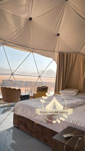 2 camas en una habitación con vistas al desierto en Rum world camp, en Wadi Rum